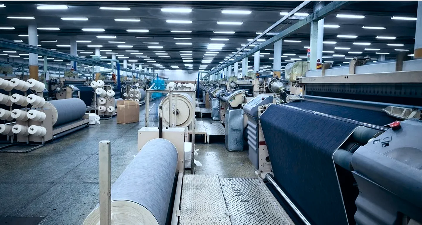 Textile manufacturing facility for rent in Tronica City Ghaziabad with industrial weaving looms and fabric rolls.
