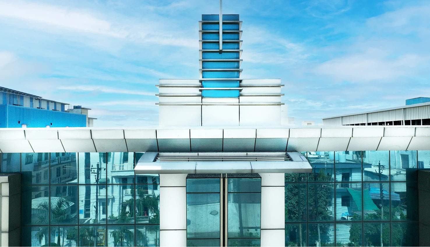 Modern manufacturing facility with blue glass facade for rent in Tronica City, Ghaziabad.