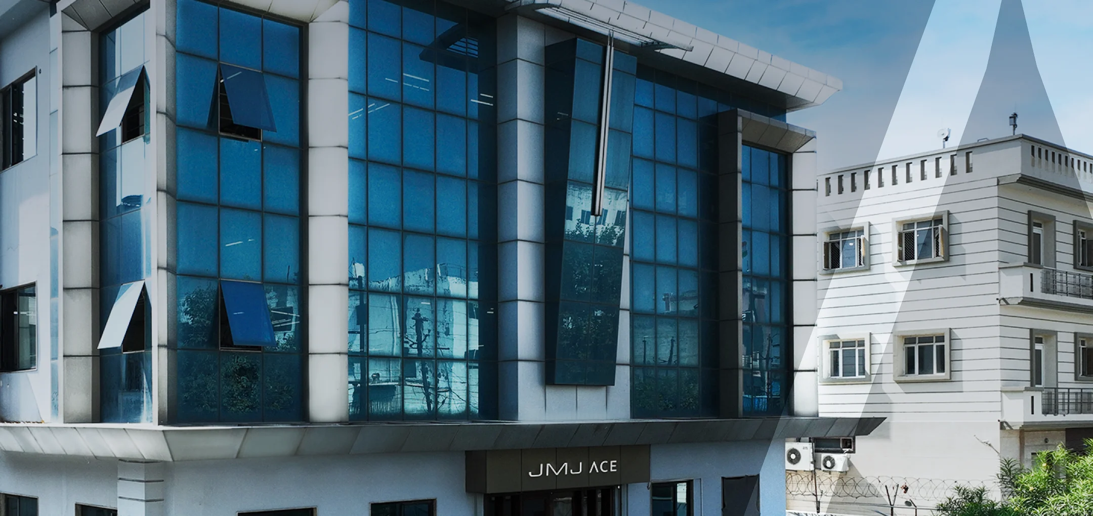 JMJ ACE manufacturing facility for rent in Tronica City, Ghaziabad featuring a modern blue glass facade.